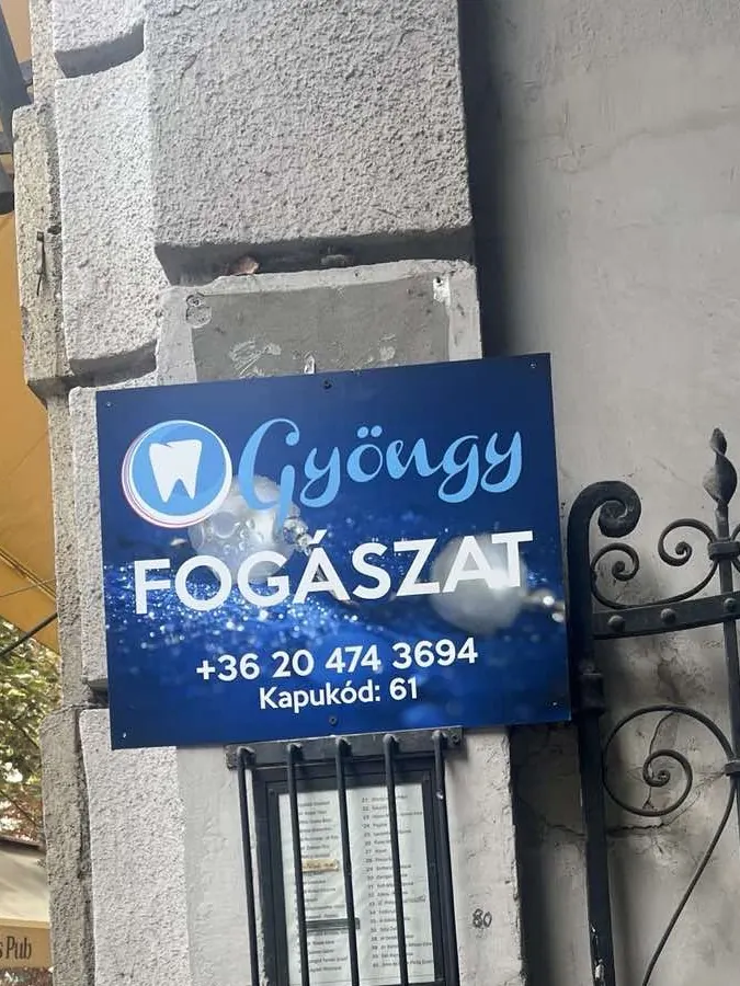 A Gyöngy Fogászat táblája a Kecskeméti utca 2. kapuja mellett, rajta a telefonszám és a kapukód